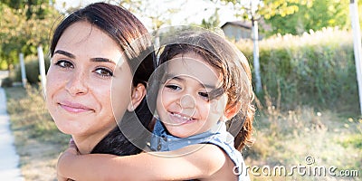 Young daughter on a piggy back ride with her mother lifestyle outdoor Stock Photo