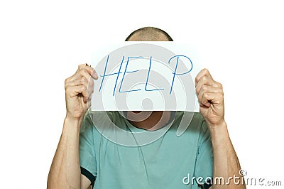 Young depressed man suffering from anxiety and feeling miserable holding help sign on paper in his hands and leaning on the white Stock Photo