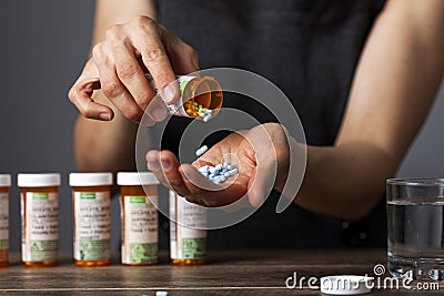A young depressed woman is taking pills out of the medication bottle Stock Photo