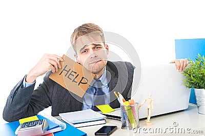 Young desperate businessman holding help sign looking worried suffering work stress at computer desk Stock Photo