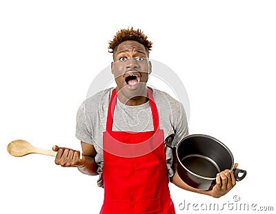 young desperate and confused black afro american man in chef apron holding cooking pot and spoon in his hands looking lost Stock Photo