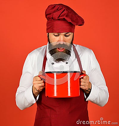 Young desperate and confused man in chef apron holding pot Stock Photo