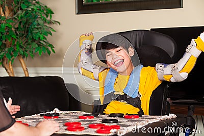 Young disabled boy in wheelchair playing checkers Stock Photo