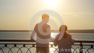 Young disabled couple looks at river at back sunset light Stock Photo