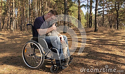 A young disabled man in a wheelchair and a dog in the park Stock Photo