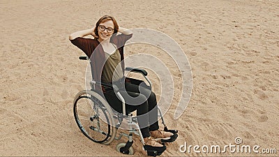 Young disabled woman on the sandy beach sitting in the wheelchair Stock Photo