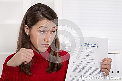 Young disappointed woman staring at business contract in german Stock Photo