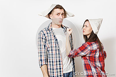 Young dissatisfied woman, man in casual clothes and newspaper hats quarrelling. Couple isolated on white background Stock Photo