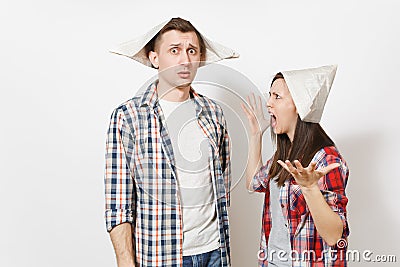 Young dissatisfied woman, man in casual clothes and newspaper hats quarrelling. Couple isolated on white background Stock Photo