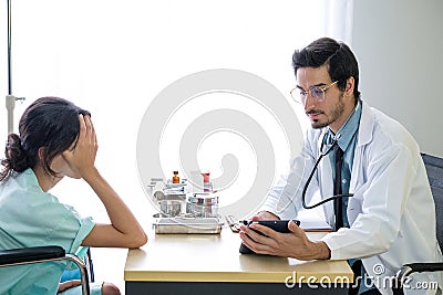 The young doctor examined the symptoms of the patients and reported the results to patients Stock Photo