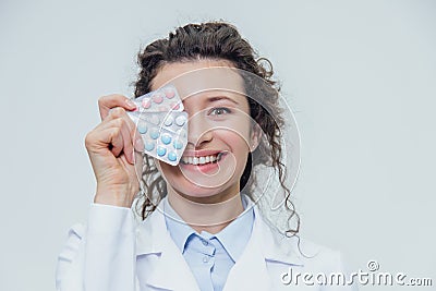 The young doctor`s daughter is on a gray background. During this, it holds three blister packs in its hands. Lifting Stock Photo