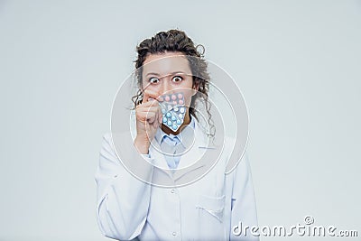 The young doctor`s daughter is on a gray background. During this, it holds three blister packs in its hands. Lifting Stock Photo