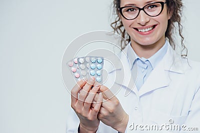 The young doctor`s daughter is on a gray background. During this, it holds three blister packs in its hands. Lifting Stock Photo