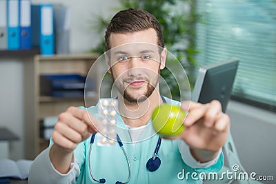 Young doctor showing apple and tablets Stock Photo