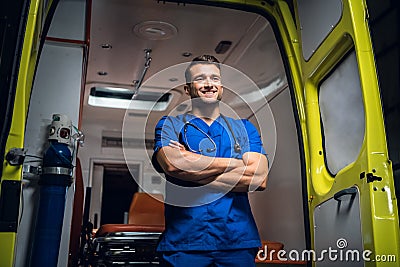 Young doctor standing and smiling in front of an an ambulance car Stock Photo