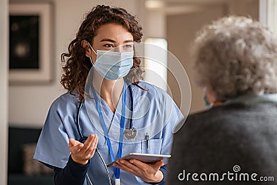 Young doctor visits senior woman with surgical mask Stock Photo