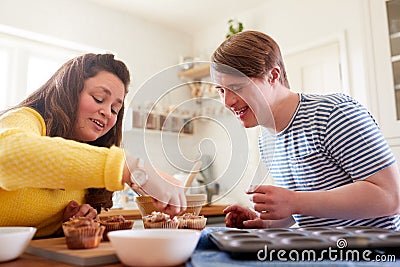 Young Downs Syndrome Couple Decorating Homemade Cupcakes With Icing In Kitchen At Home Stock Photo