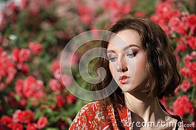 Young dreamy woman with red roses. Outdoor portrait of a romantic girl with hard sunlight. Space for text Stock Photo