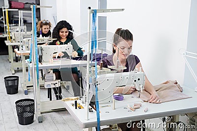 Young dressmaker women sew clothes on sewing machine in tailor studio Stock Photo