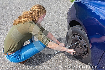 Young dutch woman changing car tire on road Stock Photo