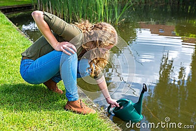 Young dutch woman filling green caster with water Stock Photo