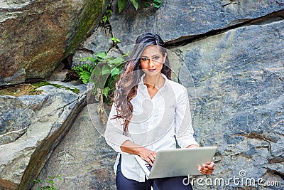 Young East Indian American Woman with long hair working on laptop computer outdoor in New York Stock Photo