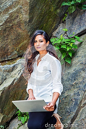 Young East Indian American Woman with long hair working on laptop computer outdoor in New York Stock Photo