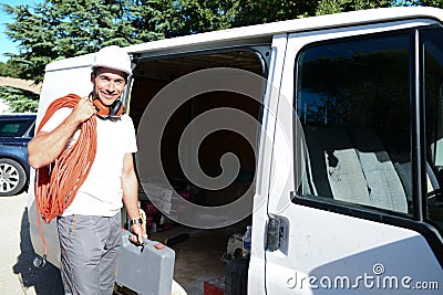 Young electrician artisan taking tools out of professional truck van Stock Photo