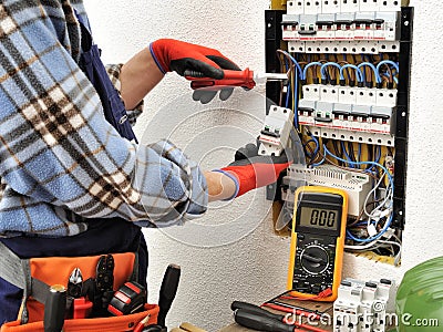 Young electrician technician at work on a electrical panel with Stock Photo