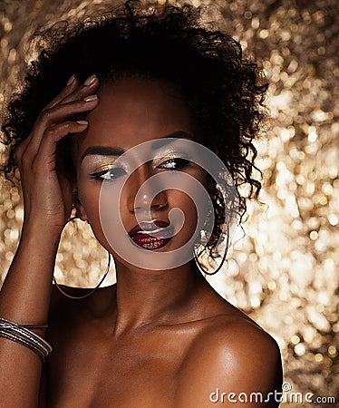 Young elegant african american woman with afro hair. Glamour makeup. Golden Background. Stock Photo