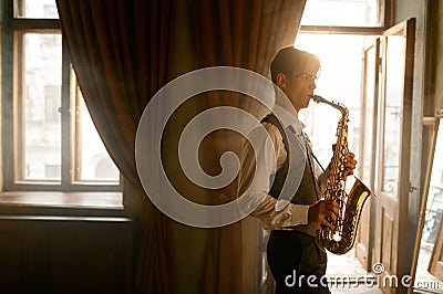 Young elegant man playing gold alto saxophone in misty room Stock Photo