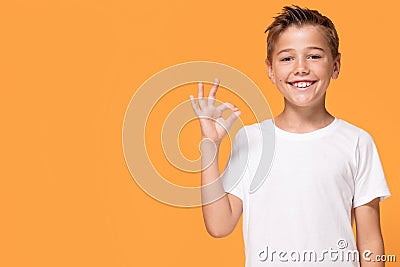 Young emotional little boy on orange studio background. Stock Photo