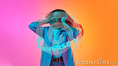 Young emotive girl in headphones with neon lettering around body isolated pink and orange background Stock Photo