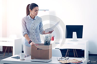 Young employee packing her stuff in box while leaving work Stock Photo