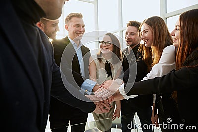 young employees joining their palms over the Desk. Stock Photo