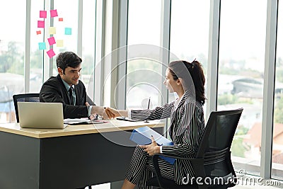 Young employers in black suits shaking hands during a meeting in the office Stock Photo