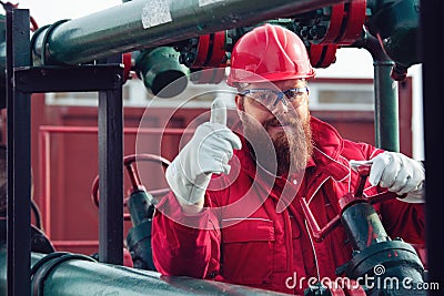 Engineer in hard-hat. Face behind pipeline machinery, fuel and oil refinery. Stock Photo
