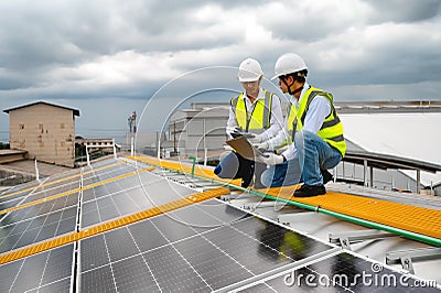 Young Engineers and Technicians Discuss and Check Quality of Installing Solar Photovoltaic Panels and Use App Technology Checking Stock Photo