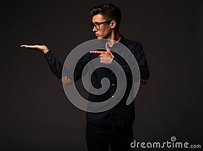 Young enigmatical man showing by hands. Stock Photo