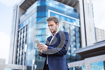 Young enterpreneur browsing internet on smartphone in city center Stock Photo