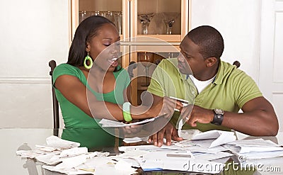 Young ethnic couple by table overwhelmed by bills Stock Photo