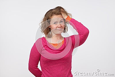 Young european woman in pink sweater looking with doubt in camera. She is confused and does not trust the news. Stock Photo