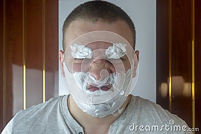 Young evil man foam beard and eyebrows in the bathroom Stock Photo