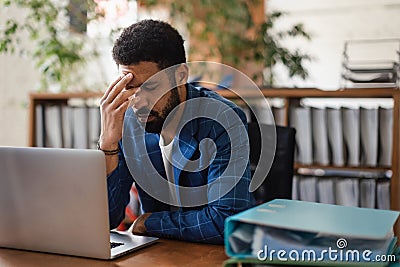 Young exhausted male employee in front of notebook in his office. Stock Photo