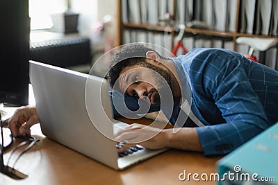 Young exhausted male employee in front of notebook in his office. Stock Photo