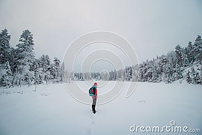 Young explorer in a colorful jacket stands in a frosty white environment in Sotkamo, Finland. Active lifestyle. Walking in wild Stock Photo