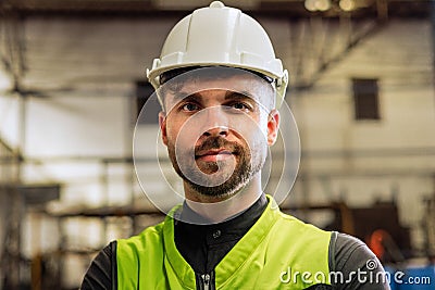 Young factory worker in hard hat standing at industry site Stock Photo