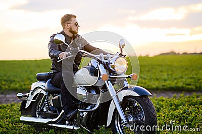 Young fair-haired brutal biker guy with a beard in sunglasses on a motorcycle Stock Photo