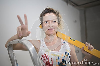 Young fair-haired curly woman makes repairs in the dwelling with construction tools. Stock Photo