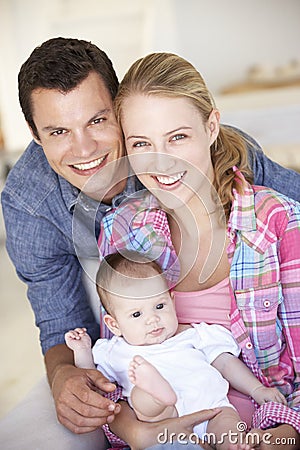 Young Family With Baby Relaxing On Sofa At Home Stock Photo